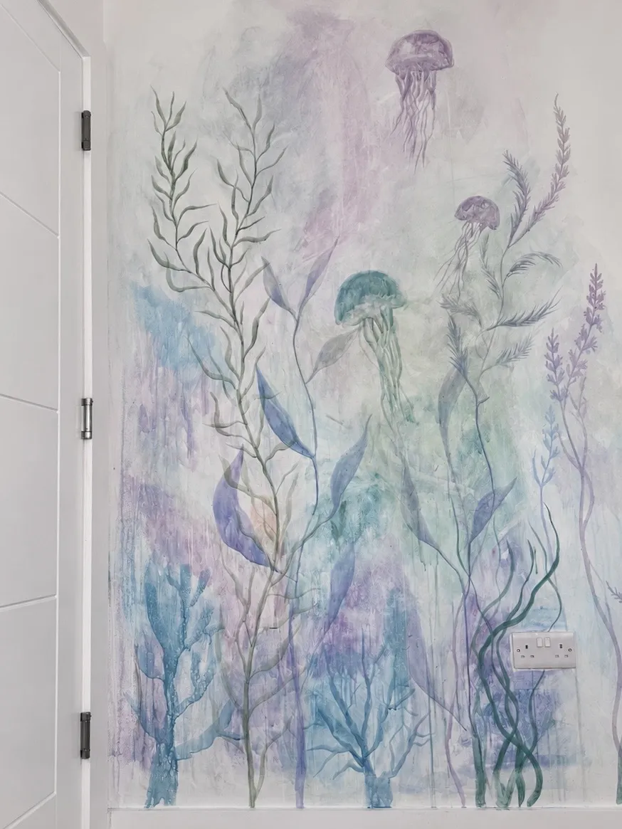 Underwater mural painted by Vera Hylands — translucent jellyfish drifting through painted kelp in soft purple and teal