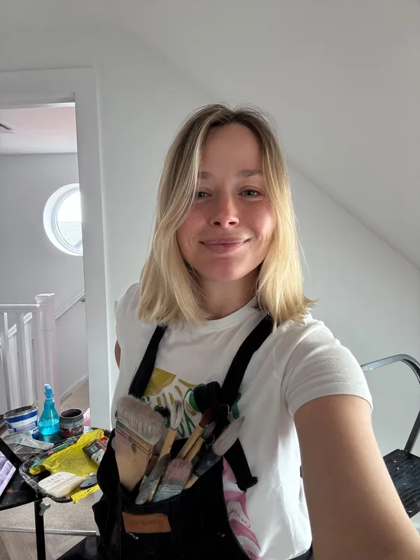 Portrait of Vera Hylands, mural artist based in Belfast — in her attic studio with paintbrushes